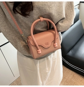 Détail du sac en similicuir rose avec texture tressée, boucle en métal et poignée ronde