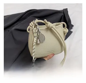 Detail of cream white pebbled leather bucket bag with knot handle and tennis charm