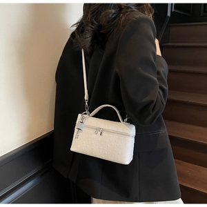 Detailed back view of a white ostrich embossed crossbody bag with silver hardware on a model