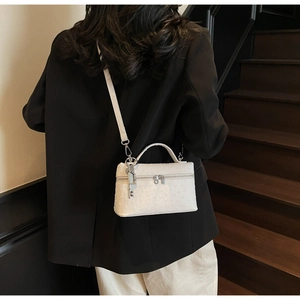 Detail of white ostrich pattern bag with silver key charm on a black blazer