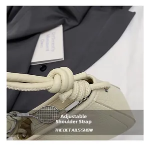 Detail of lychee textured leather bucket bag with knotted strap and tennis racket charm