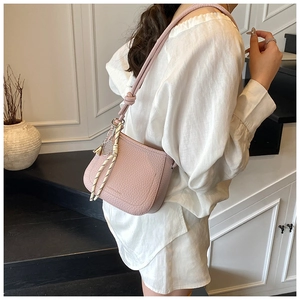 Pink lychee texture crossbody bucket bag with decorative woven charm and metal bead detail