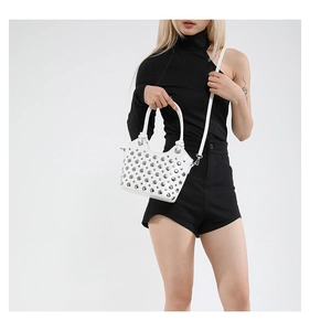 Detail view of white bucket bag featuring silver punk rivets and sturdy round handle