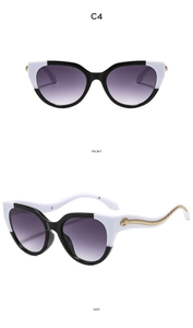 Détail de lunettes œil de chat avec serpent doré sur monture bicolore noir et blanc
