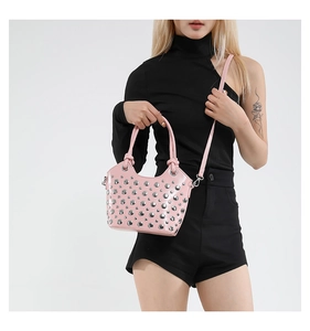 Close-up of pink patent leather bucket bag with silver studs and thin crossbody strap