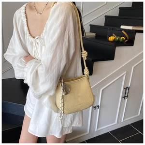 Detail showing the light yellow bucket bag with a knotted strap and fashion logo