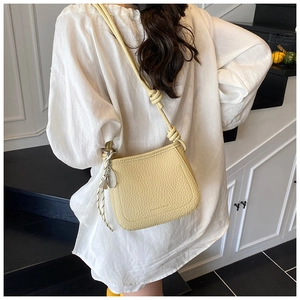 Detail showing the adjustable knot shoulder strap on a yellow textured bucket bag