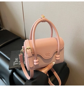 Détail du sac à bandoulière rose clair avec texture tissée et logo embossé