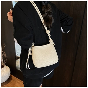 Detail showing creamy white litchi pattern leather texture and knotted wide shoulder strap
