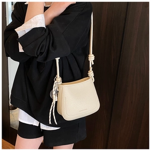 Detail of cream lychee leather texture and woven rope strap on minimalist crossbody bag
