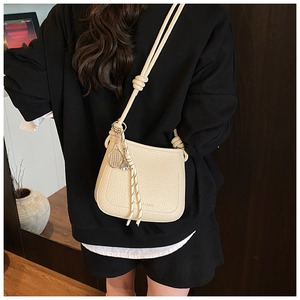 Detail view of cream lychee texture leather bucket bag with tennis racket charm
