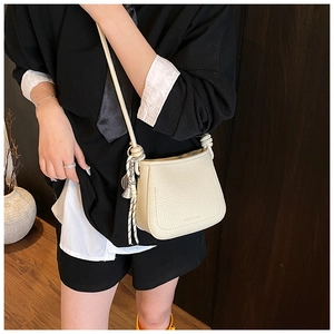 Detail of cream lychee pattern leather crossbody bag with knot strap and tassel charm