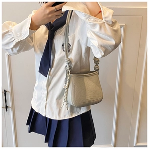 Close-up of light gray bucket bag with lychee texture and unique knot shoulder strap