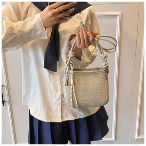 Close-up of light gray bucket bag with knotted handle and metal sphere charm detail