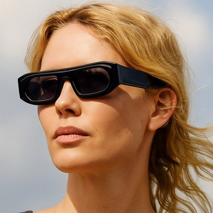 Close-up of black oversized rectangular sunglasses with thick frames on model