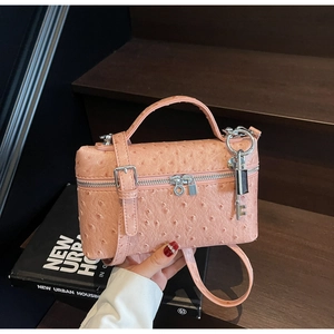 Detail of pink ostrich texture handbag with dual silver zippers and adjustable strap