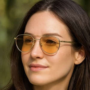 Close-up of stylish double bridge aviator sunglasses with gold metal frames and amber lenses