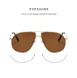 Close-up of classic pilot sunglasses with gold metal double-bridge frame and brown lenses