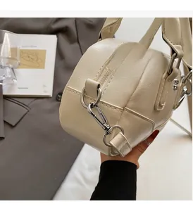 Détails du sac boston blanc cassé avec texture litchi et finitions en métal argenté