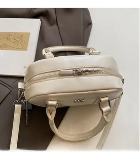 Détail d'un sac Boston en cuir blanc cassé avec une fermeture éclair en métal fluide