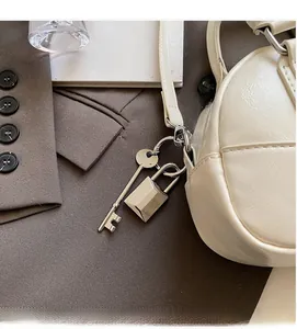 Détail du pendentif serrure argentée sur un sac Boston en cuir blanc avec finitions métal