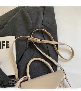 Detail view of beige oily faux leather bag with tennis racket charm and shoulder strap