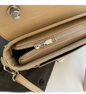 Close-up of the smooth silver zipper and interior compartment of the beige leather bag