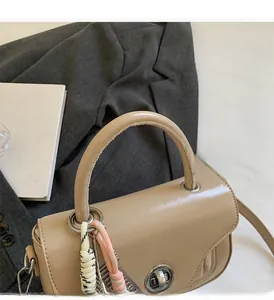Detail of beige faux leather handbag with round handle and woven rope charms