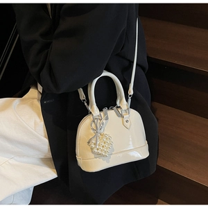 Dettaglio borsa a conchiglia in pelle cerata bianco panna con ciondolo a cuore di perle