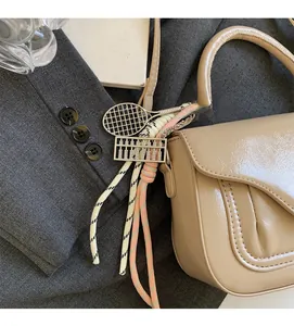 Close-up of beige patent leather bag with tennis racket and abacus charm detail