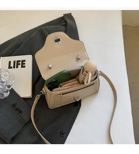 Detail view of beige leather bag interior showing capacity for phones and a mini umbrella