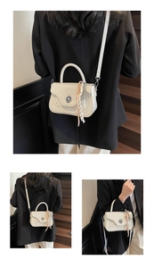 Detailed view of beige crossbody bag featuring round gold clasp and silk scarf charm