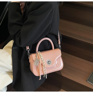 Detail of pink oil wax leather handbag with silver twist lock and woven charm