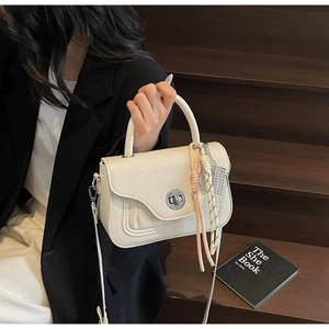 Detail of cream white leather handbag with silver twist lock and decorative rope pendant