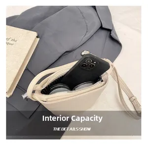 Internal capacity of minimalist cream bucket bag showing smartphone and cosmetics