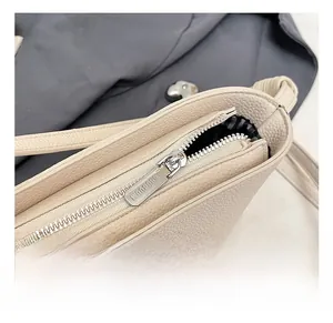 Close-up of beige lychee grain leather bag featuring silver zipper and striped lining