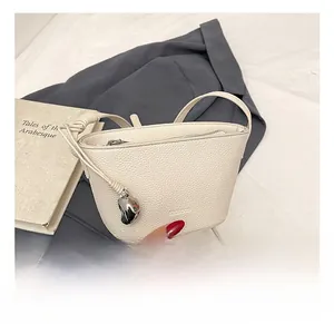 Detail showing creamy white pebble leather bucket bag with silver heart charm and strap