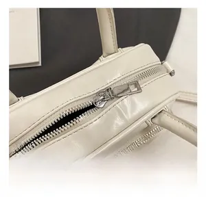 Close-up of premium silver metal zipper and hardware on the beige fashion handbag