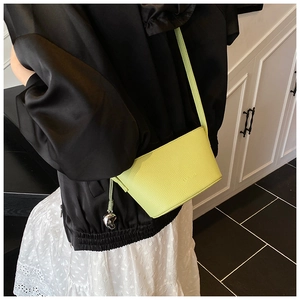 Detail of lime green bucket bag with lychee texture and silver heart pendant
