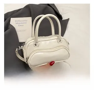 Detail of creamy white crossbody bag showing zipper pocket and smooth glossy texture