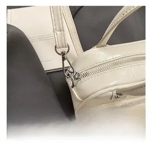 Macro shot of silver metal zipper and detachable strap hook on cream faux leather bag