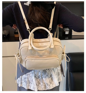 Detail view of cream white PU backpack with double round handles and bow tie decorations