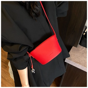 Detail of red leather bucket bag featuring a metallic heart pendant and black blazer outfit