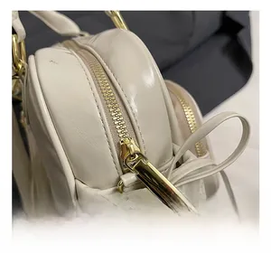 Detailed close-up of premium gold metal zipper and stitching on the cream leather tote bag