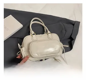 Detail view of cream leather Boston bag showing front zipper pocket and slim strap