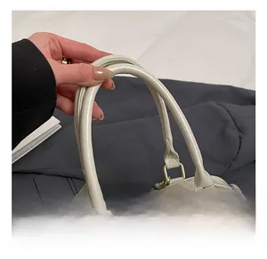 Detail of beige tote bag with comfortable double handles and gold metal connectors