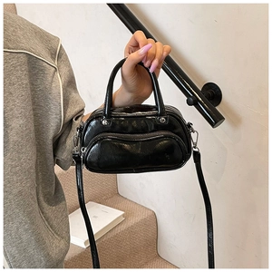 Detail of glossy black mini crossbody bag with multi-zipper pockets and metal hardware