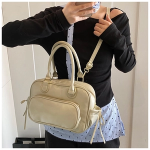 Detailed view of beige Boston handbag featuring front zipper and drawstring side accents