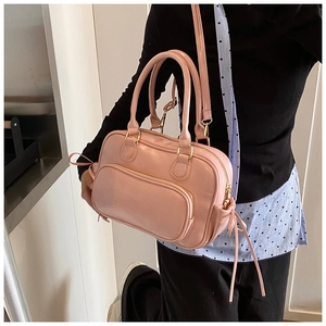 Detail view of pink PU leather handbag showing a front zipper pocket and side bow drawstring