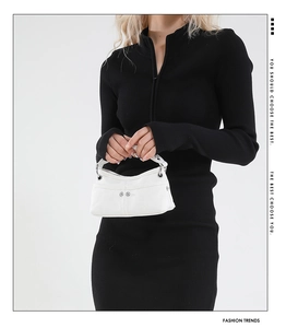 Dettaglio di una borsa a mano bianca testurizzata con borchie metalliche e stile Y2K